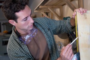 Hispanic man measuring piece of wood